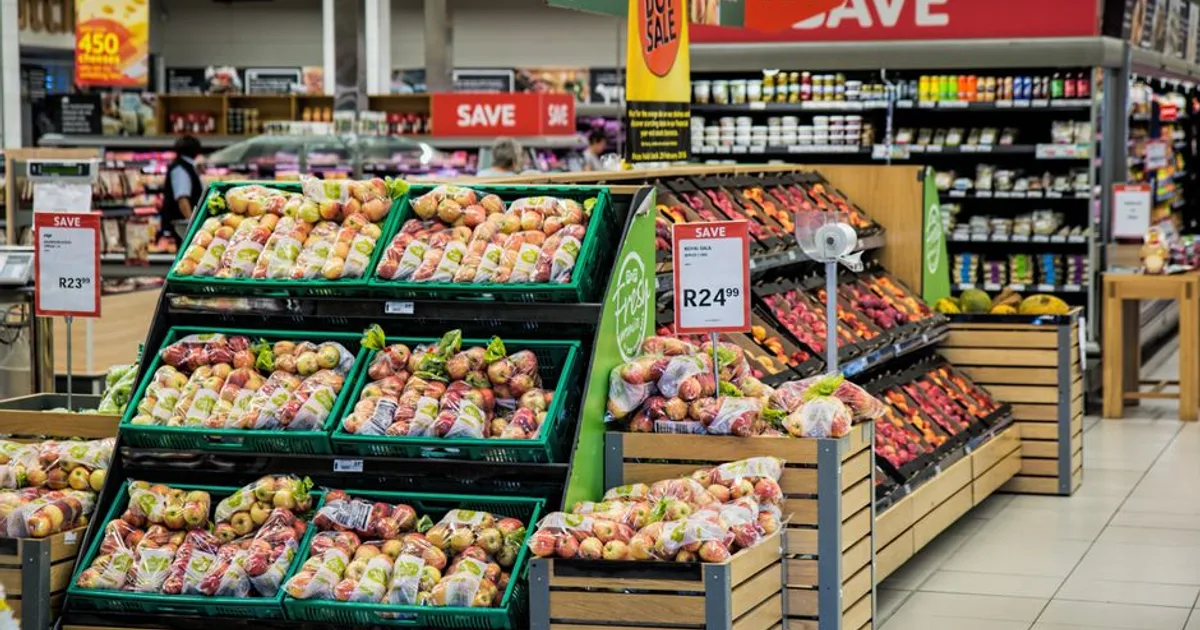 Colorful produce aisle in a supermarket showcasing fresh apples with discount signage.