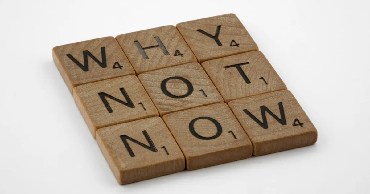 a scrabbled wooden block that says why not now